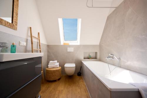 a bathroom with a tub and a toilet and a sink at Landhaus Esperort in Ahrenshoop