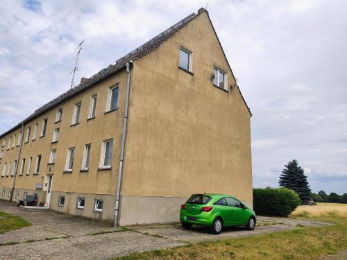 einem grünen Auto, das vor einem Gebäude parkt in der Unterkunft Dachgeschoss im Ostblock in Annaburg