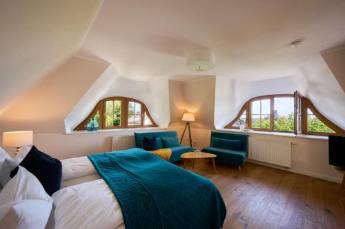 a bedroom with a bed and two chairs and a tv at Landhaus Esperort in Ahrenshoop