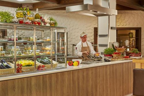 a chef standing behind a counter in a kitchen at H+ Hotel Willingen in Willingen