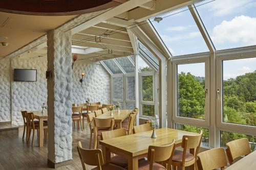 a dining room with tables and chairs and windows at H+ Hotel Willingen in Willingen