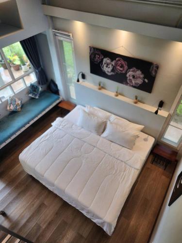 a large white bed in a room with two windows at บ้านสวนปรีดา-Preda Garden Home in Sam Phran
