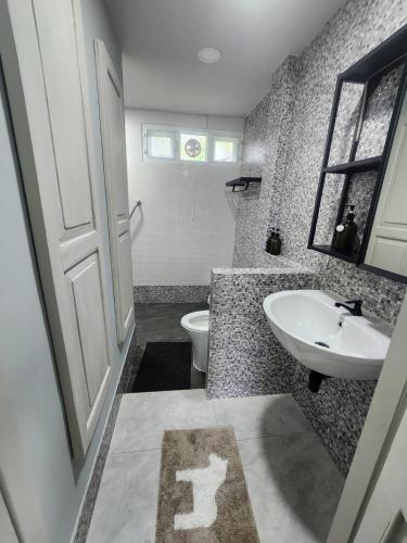 a bathroom with a white sink and a toilet at บ้านสวนปรีดา-Preda Garden Home in Sam Phran