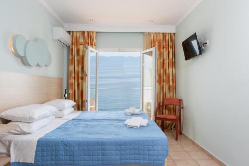 a bedroom with a blue bed with a view of the ocean at Corfu Maris in Benitses