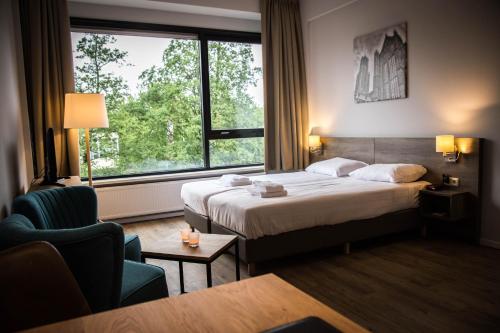 ユトレヒトにあるユトレヒトシティアパートメンツ ハイジンガラーンのベッドと大きな窓が備わるホテルルームです。