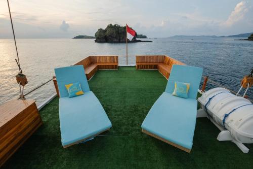 a boat with two blue chairs on the water at Luxury Private Phinisi Sailing in Komodo island in Labuan Bajo