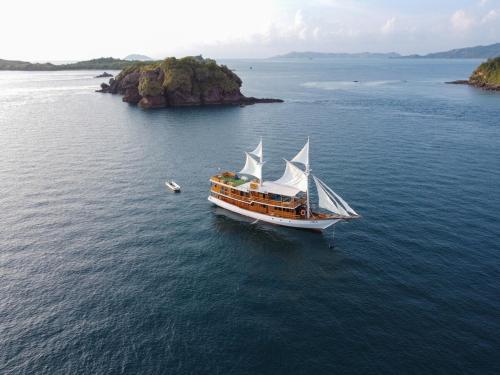 a boat in the water near a small island at Luxury Private Phinisi Sailing in Komodo island in Labuan Bajo
