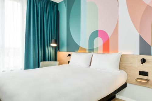 a bedroom with a bed and a colorful wall at B&B HOTEL Luxembourg Centre Cloche d'Or in Luxembourg