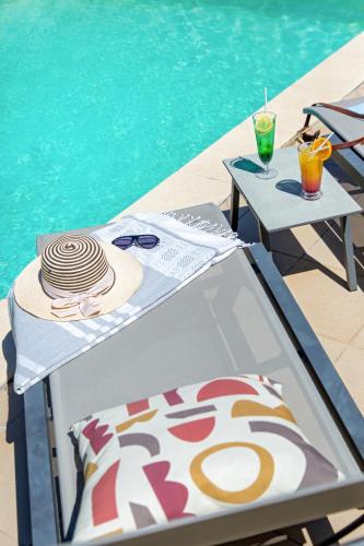 a table with a hat and glasses next to a swimming pool at ibis Salon de Provence in Salon-de-Provence