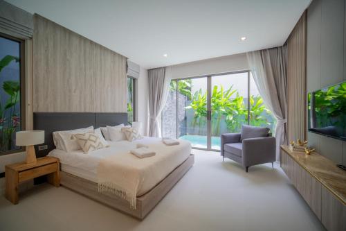 a bedroom with a bed and a chair and a television at 3BR Villa Z by NLA in Ban Pak Lak