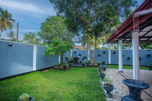 a backyard with a fence and a yard with plants at Sanda Villa Kosgoda in Kosgoda