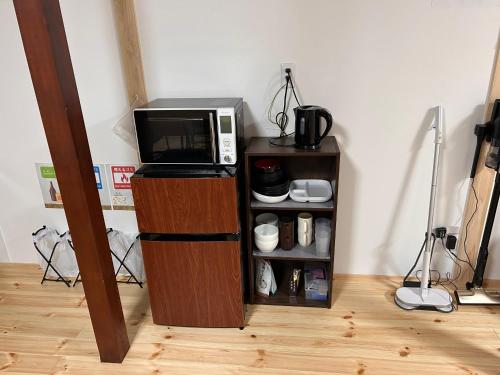 a microwave sitting on top of a wooden stand next to a shelf at 奈良井駅徒歩10分中山道奈良井宿古民家一棟貸し御宿美里屋 in Shiojiri