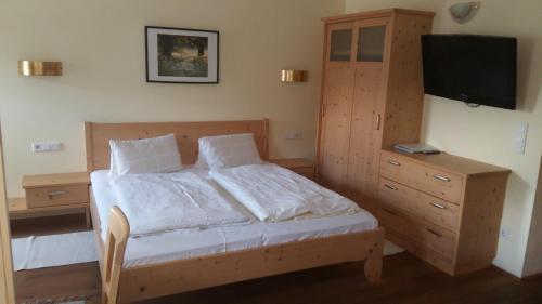 a bedroom with a bed and a dresser with a television at Forellenstube in Lofer