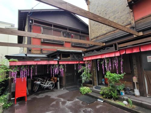an outside view of a building with flowers hanging from it at Benidaruma - Dango in Kyoto