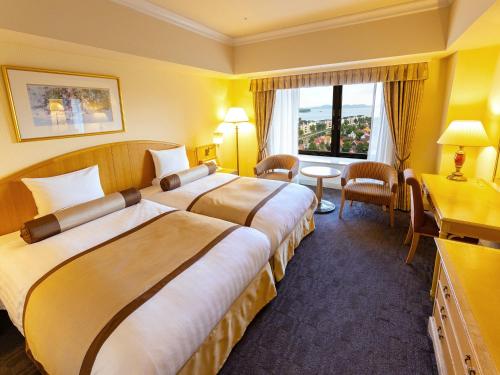 a hotel room with two beds and a desk at Hotel Okura JR Huis Ten Bosch in Sasebo