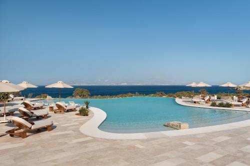 a large swimming pool with chairs and umbrellas at Vione Paros in Ambelas