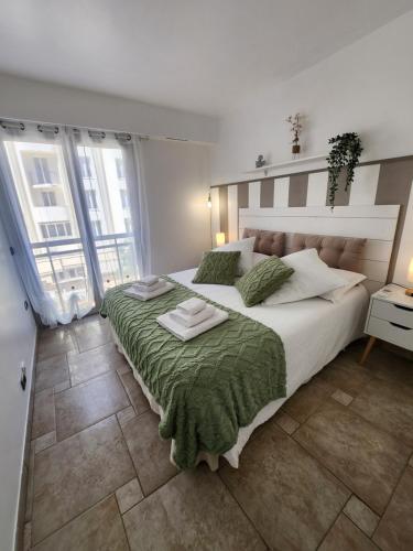 une chambre avec un grand lit avec une couverture verte dans l'établissement Cannes Paradis, à Cannes
