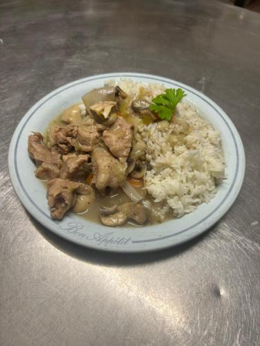 a plate of food with meat and rice on a table at le Belvédère Maison d hotes in Sainte-Anne