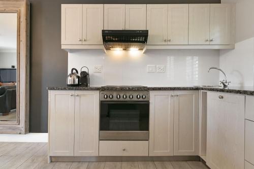 a kitchen with white cabinets and a stove top oven at Winelands Golf Lodges 24 in Stellenbosch
