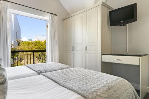 a bedroom with a bed and a tv and a window at Winelands Golf Lodges 24 in Stellenbosch