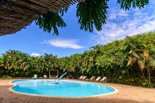 una piscina con sedie e alberi sullo sfondo di Le Chat'o Park Hotel Ivato Airport NAVETTE GRATUITE H24 a Antananarivo