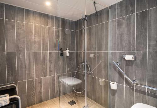 a bathroom with a shower with a toilet and a sink at B&B HOTEL Limoges 3 in Limoges
