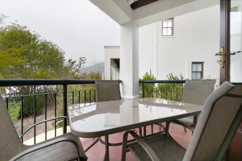 une table blanche et des chaises sur un balcon dans l'établissement Winelands Golf Lodges 26, à Stellenbosch