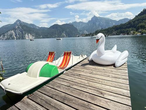 a dock with a swan and two boats on a lake at Apartmenthotel 's Mitterndorf in Traunkirchen