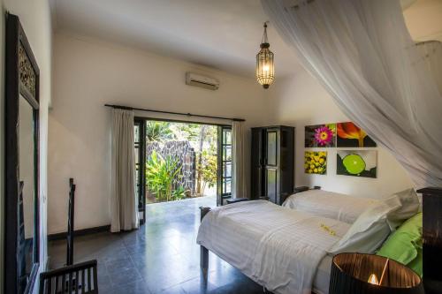 Un dormitorio con dos camas y una puerta corrediza de cristal. en Villa Rumah Rindu, en Lovina