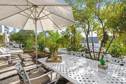 a white table with an umbrella and some chairs at Winelands Golf Lodges 28 in Stellenbosch