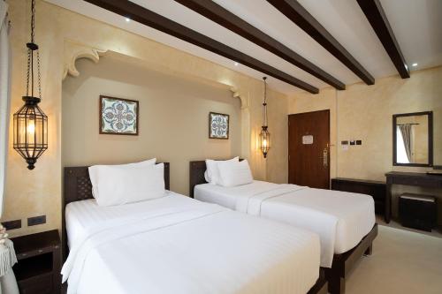 two white beds in a room with a piano at Dewan Bangkok in Bangkok