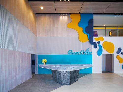 a lobby with a counter and a sign on the wall at Quest Vibe Dewi Sri Bali in Legian
