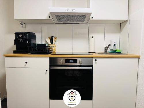 a kitchen with white cabinets and a black oven at Family M Apartments 16-17-18 in Sempach