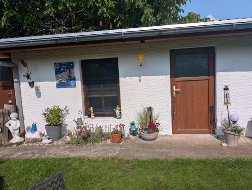 a white house with a brown door and some plants at Bungalow bei Warnemünde in Elmenhorst