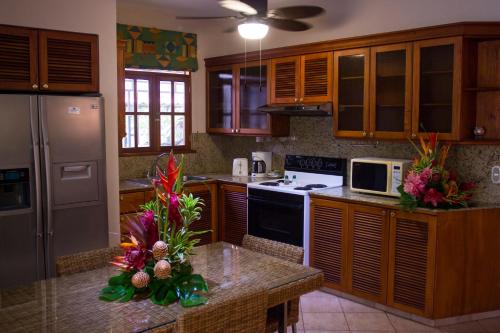 a kitchen with wooden cabinets and a counter with flowers on it at Villa del Sueño in Playa Hermosa