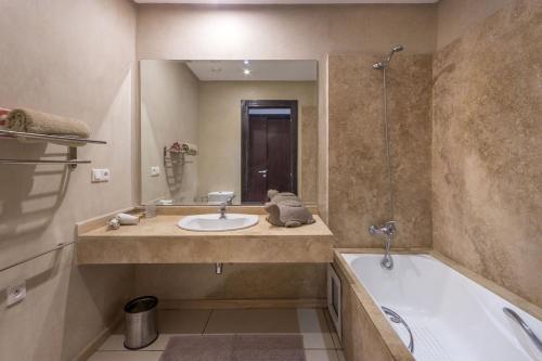 a bathroom with a sink and a tub and a mirror at Apartment with Private Rooftop & Jaccuzzi in Marrakech