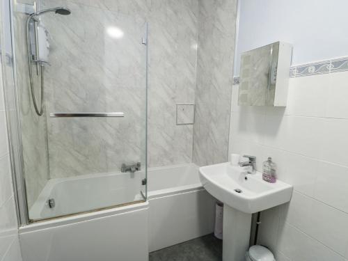 a white bathroom with a sink and a shower at Lady of the Lake Suite in Holyhead