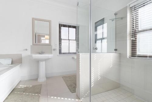 a white bathroom with a shower and a sink at Winelands Golf Lodges 33 in Stellenbosch