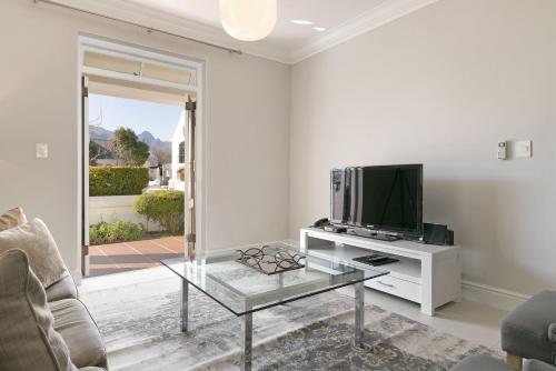 a living room with a tv and a glass table at Winelands Golf Lodges 33 in Stellenbosch