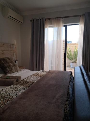 a bedroom with a bed and a sliding glass door at Villa Mariss Guesthouse in Kraaifontein