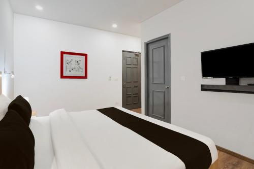 a white bedroom with a bed and a flat screen tv at Super Townhouse Gomti Nagar Sector 6 Near Ekana Stadium in Lucknow