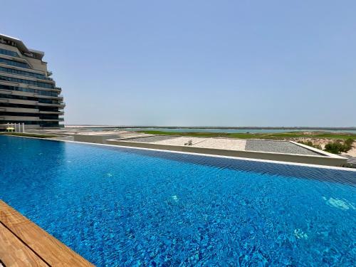 a swimming pool with a view of the ocean at Stylish 1BR in Mayan, Yas Island in Abu Dhabi