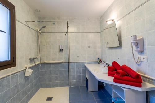 a bathroom with a sink and a shower with red towels at Maison Liz in Castelnaud La Chapelle