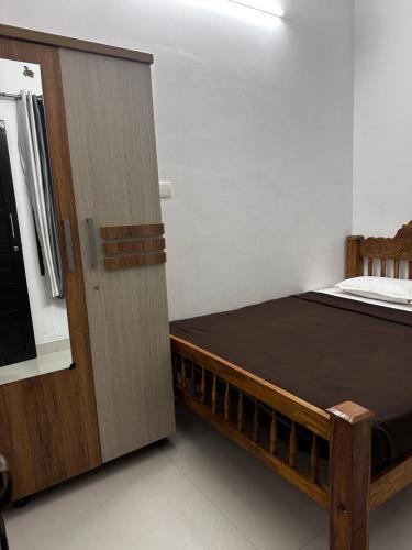 a bedroom with a bed and a wooden cabinet at Yatri Haven Varkala in Varkala