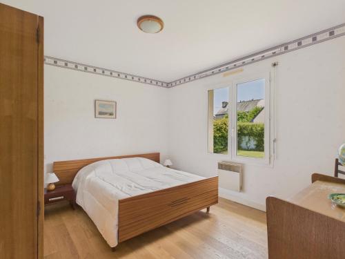 a white bedroom with a bed and two windows at Maison de plain-pied pour 4 - jardin et terrasse in La Forêt-Fouesnant