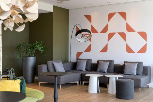 a living room with a couch and tables at Mercure Hotel Hannover Mitte in Hannover