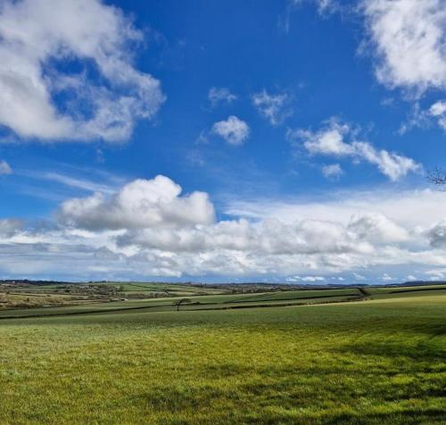 a green field with a blue sky and clouds at Moorhead Country Holidays in Bideford