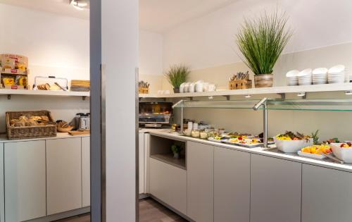 a kitchen with white cabinets and lots of food at NOVALIS Hotel by AURUM Dresden in Dresden