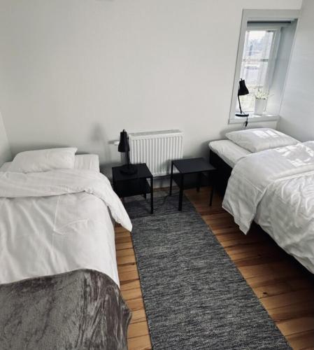 a white bedroom with two beds and a window at Litet hus nära Värnamo 