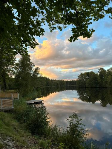 a view of a lake at sunset with a bench at Litet hus nära Värnamo 
